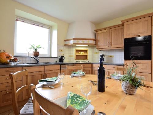 una cocina con una mesa de madera y una botella de vino en Comfortable Cottage in Neufmoulin with Meadow View en Houffalize
