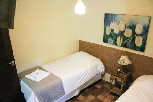 a room with two beds and a painting of flowers at Gamboa Eco Refugio Pousada in Iporanga