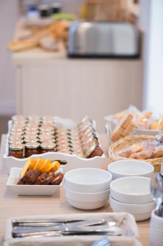 a table topped with plates and bowls of food at The Originals City, Hôtel Chantecler, Le Mans in Le Mans