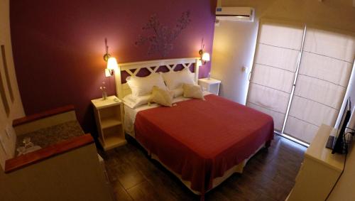 1 dormitorio con 1 cama con colcha roja en Hostería Magnolia en Villa Gesell