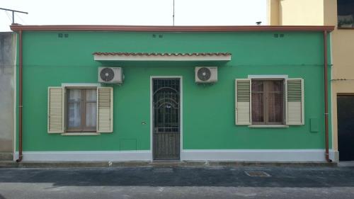 a green building with two windows and a door at Da Andrea & Viola in Terralba