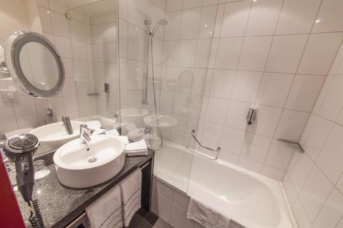 a white bathroom with a sink and a shower at Novina Hotel Tillypark in Nürnberg