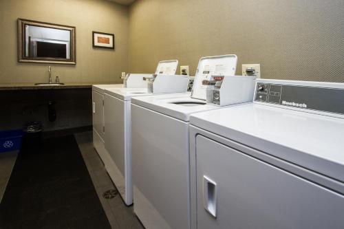 a laundry room with a row of washers and dryers at Comfort Suites Kelowna in Kelowna