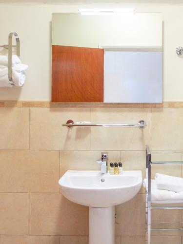a bathroom with a white sink and a mirror at Elmdon Lodge in Birmingham