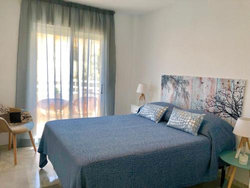 - une chambre avec un lit bleu et une fenêtre dans l'établissement Luxury Doña Carlota, à Torremolinos
