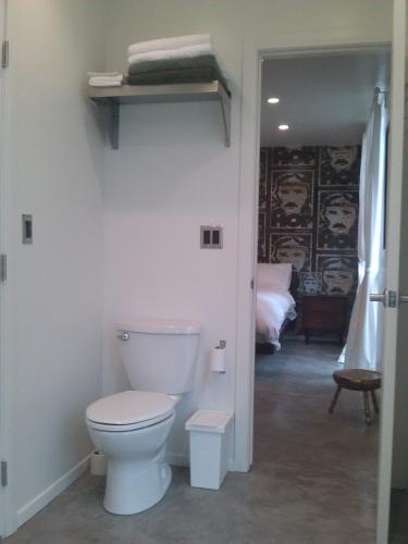 a bathroom with a white toilet and a bedroom at Ocean Front Vortex Female Hostel private rooms Free bikes in Los Angeles