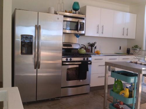 a stainless steel refrigerator in a kitchen with white cabinets at Ocean Front Vortex Female Hostel private rooms Free bikes in Los Angeles
