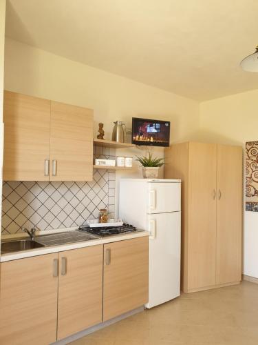 uma cozinha com armários de madeira e um frigorífico branco em Trenasse em Marsala