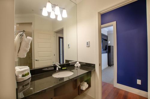 baño con lavabo y espejo grande en Premiere Suites - St. John's Signal Hill Gate en San Juan de Terranova