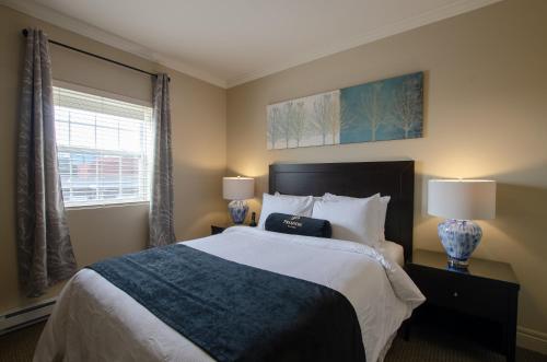 a bedroom with a bed with two lamps and a window at Premiere Suites - St. John's Signal Hill Gate in St. John's