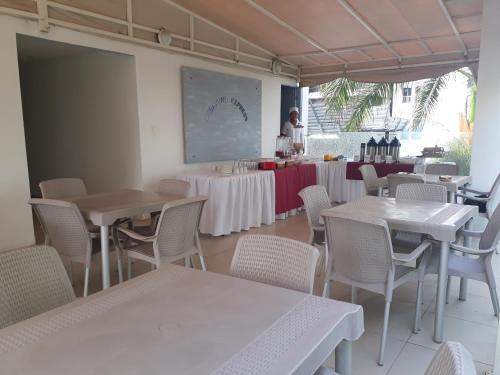 un restaurant avec des tables et des chaises et une femme en arrière-plan dans l'établissement Mintaka Hotel + Lounge, à Carthagène des Indes