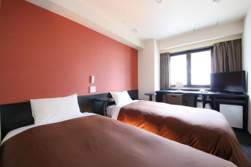 a hotel room with two beds and a desk at Urbain Tokyo Haneda Kamata in Tokyo
