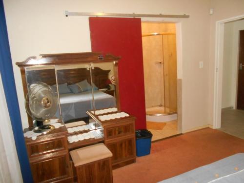 a bedroom with a bed and a vanity with a mirror at Pilot Inn Accommodation in Kempton Park