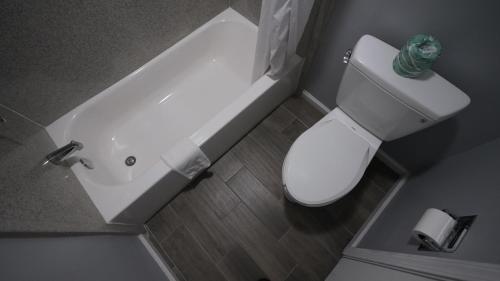 a bathroom with a white toilet and a bath tub at Columbus Inn and Suites in Columbus