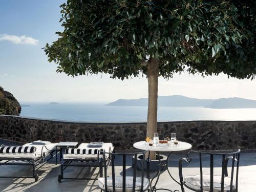 a table and chairs under a tree on a patio at San Antonio - Small Luxury Hotels of the World in Imerovigli