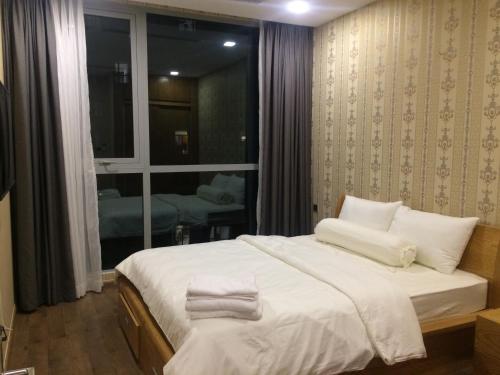 Schlafzimmer mit einem Bett mit weißer Bettwäsche und einem Fenster in der Unterkunft Capitalland's Service Apartment Park 7 Vinhomes in Ho-Chi-Minh-Stadt