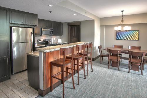 
a kitchen with a refrigerator, microwave, table and chairs at Blue Mountain Resort Mosaic Suites in Blue Mountains
