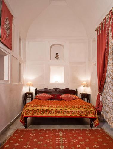 a bedroom with a bed with red pillows on it at Neemrana Fort-Palace in Neemrana