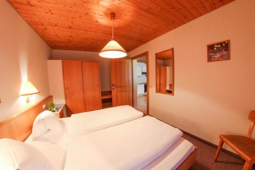 1 dormitorio con 2 camas blancas y techo de madera en Pension Kröll en Sankt Jakob in Defereggen