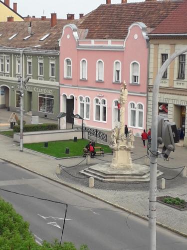 une rue avec une fontaine en face des bâtiments dans l'établissement Tavas Barlang Apartman Tapolca, à Tapolca