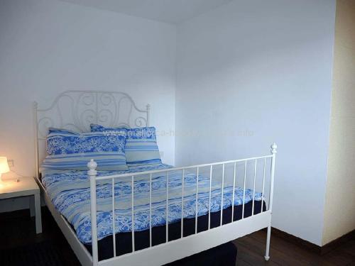 a white bed with blue sheets and pillows on it at Appartement Sant Elmo, Cala Conills, WIFI in Sant Elm