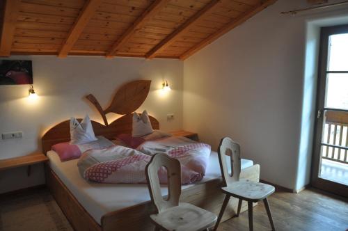 1 Schlafzimmer mit 2 Betten und 2 Stühlen in der Unterkunft Obergostnerhof in Klausen