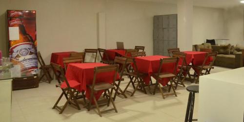 a group of red tables and chairs in a room at Vila Suítes Coliving in Vila Velha