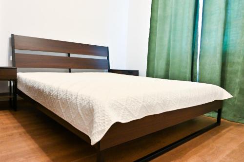 un letto in una camera da letto con tende verdi di Sophia's Cozy Apartment a Mediaş