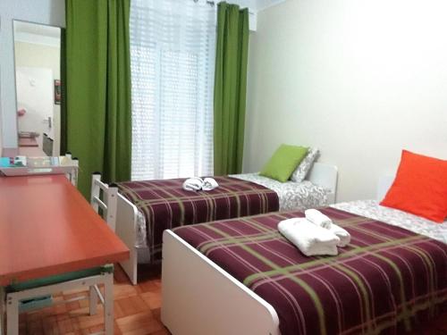 two beds in a room with green curtains at Apartament's Veiga Tejo in Lisbon
