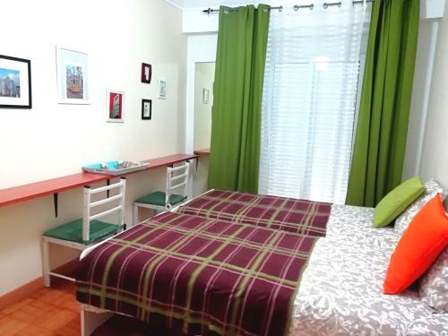 a bedroom with a bed and a desk and green curtains at Apartament's Veiga Tejo in Lisbon