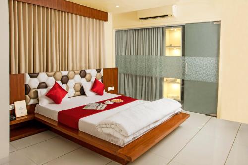 a bedroom with a large bed with red pillows at Hotel Fun City in Navsāri