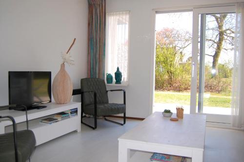 ein Wohnzimmer mit einem TV, einem Stuhl und einem Tisch in der Unterkunft Amelander Kaap 109 in Hollum