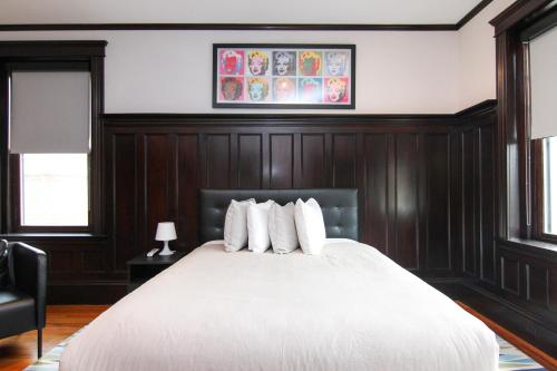 a bedroom with a large white bed with wood paneling at A Stylish Stay with a King Bed and Heated Floors #27 in Brookline
