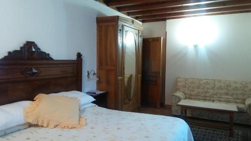 een slaapkamer met een bed en een bank erin bij Posada Santa Eulalia in Villanueva de la Peña