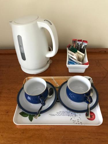 a tray with two cups and a tea pot and spoons at Barnfield Bed and Breakfast in Downton