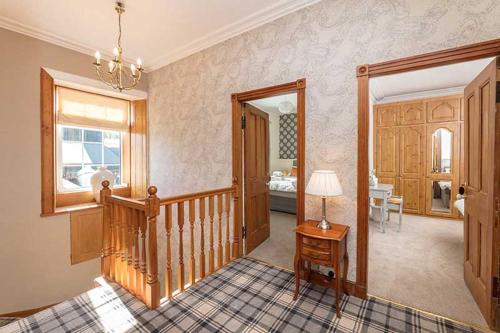 a living room with a staircase and a table with a lamp at Maxwelston Farmhouse in Girvan