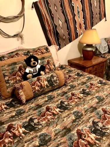 a teddy bear sitting on top of a bed at Cowboy's Lodge in Gardiner