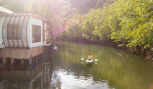 a person in a kayak in a river next to a house at Escape Life Koh Kood in Ko Kood