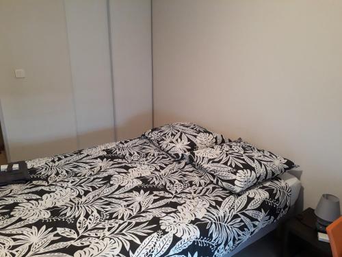 - un lit avec une couverture noire et blanche dans l'établissement Studio équipé face CHU, à Saint-Priest-en-Jarez