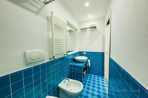 a blue tiled bathroom with a toilet and a sink at Sea House Porto Ercole in Porto Ercole