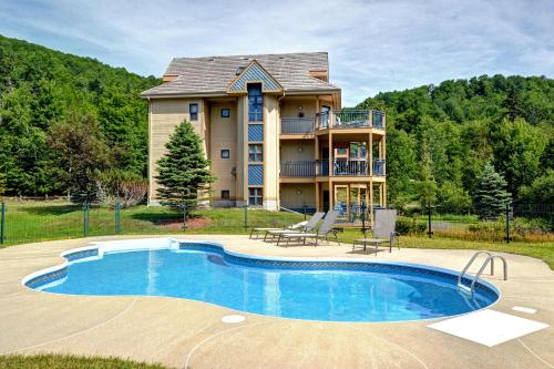 a house with a swimming pool in front of a house at Condo Jardins du Village Mont-Tremblant in Mont-Tremblant