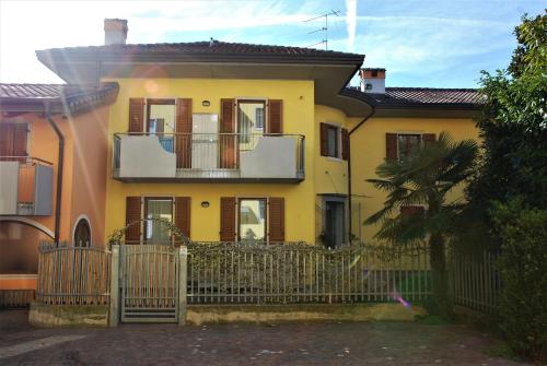 une maison jaune avec une clôture devant elle dans l'établissement ECO - Casa Vacanze Arcobaleno, à Arco