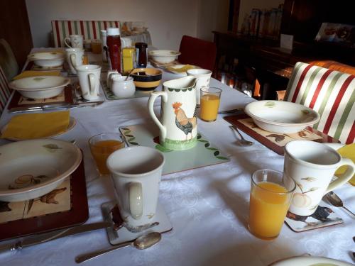 a table topped with plates and cups and orange juice at Highfields Farm B&B in Stone