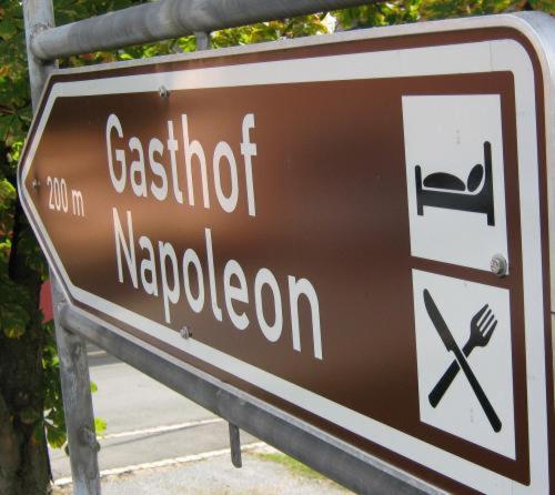 un letrero marrón para un restaurante y un letrero para un napoleón en Gasthof Napoleon, en Selbitz