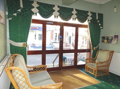 a room with two chairs and a glass door at Beeton Villas Holiday Apartments in Blackpool