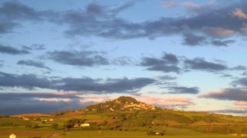 a hill in a field under a cloudy sky at Château de la Vernède, la Grande Vernède in Saint-Rémy-de-Chargnat