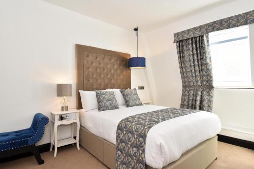 a bedroom with a large bed and a blue chair at The Lane - Boutique Residence in Galway