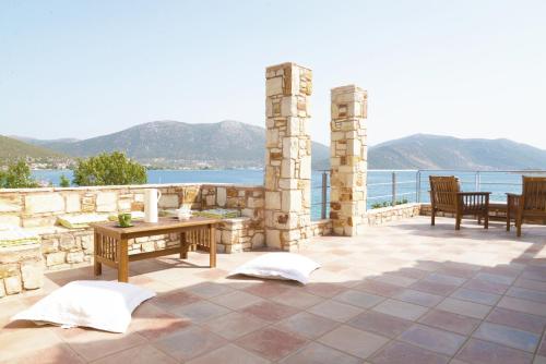 a patio with two benches and a table and the water at blueline guesthouse in Áyios Dhimítrios