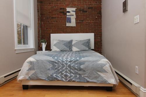1 dormitorio con 1 cama con pared de ladrillo en Stylish Downtown Studio in the SouthEnd, C.Ave# 3, en Boston