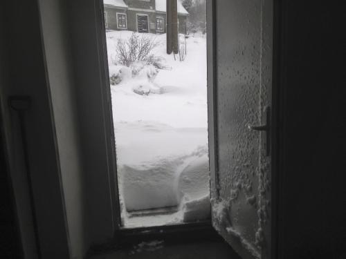 a door with a view of a snow covered yard at Kanada Inn u Klínovce in Vejprty